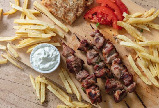 Souvlaki dish greek meat food grilled skewers and pita bread on wooden table overhead